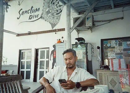 Man using smartphone at Bali Center Dive, Nusa Penida diving spot.