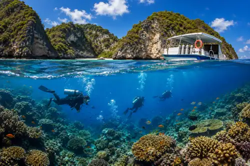 Scuba divers exploring coral reefs near Nusa Penida with boat in background.